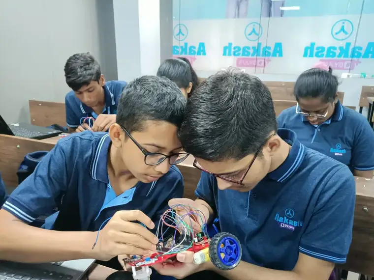 Two students building a robot car in class