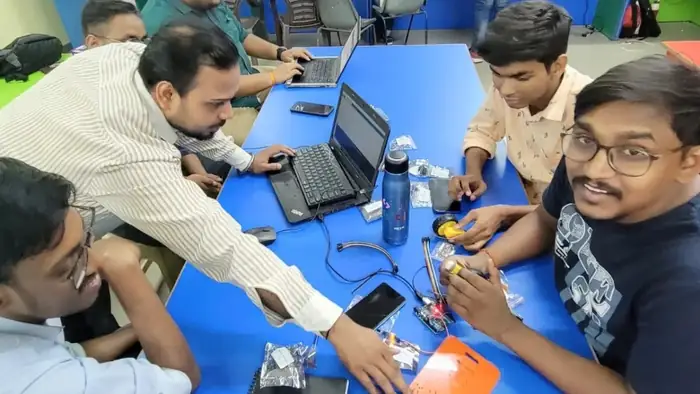 Trainers and students building with robotics kits around a table