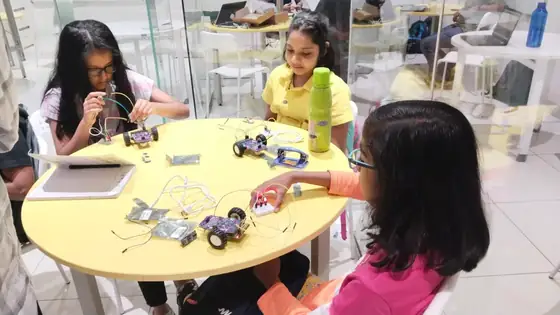 Girls building electronics kits at a workshop table